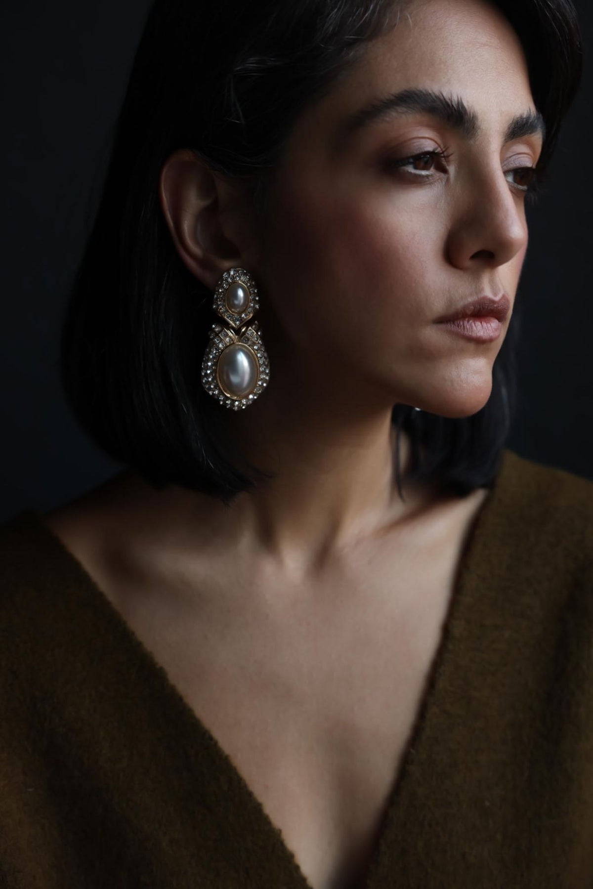 Model wearing two-tier faux pearl and rhinestone drop earrings, portrait