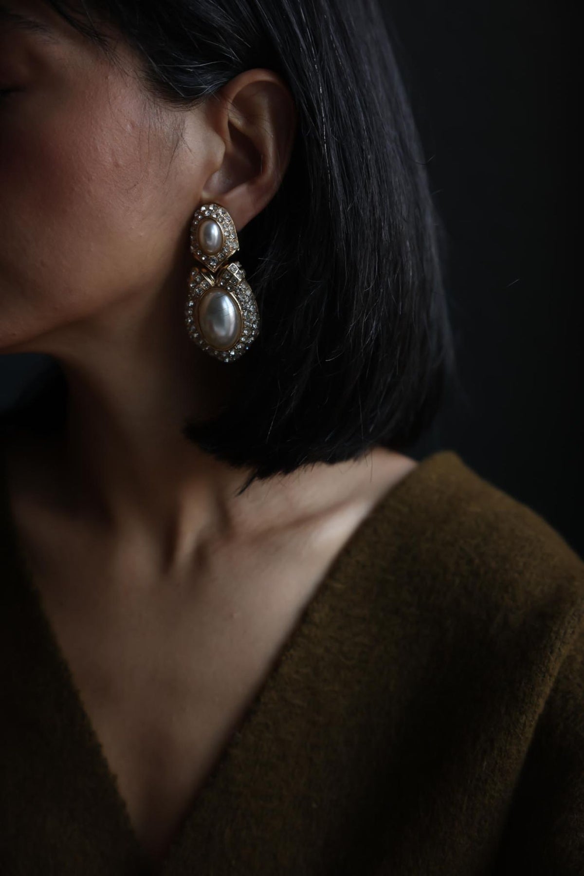 Side view of the gold tone pearl drop clip-on earring on the ear