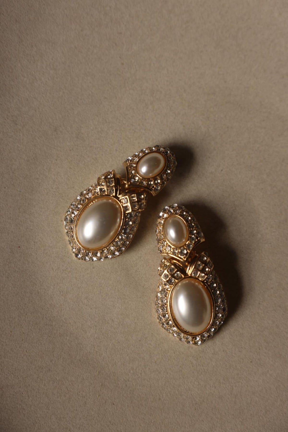 Pair of oval faux pearl and pavé rhinestone drop earrings laid flat