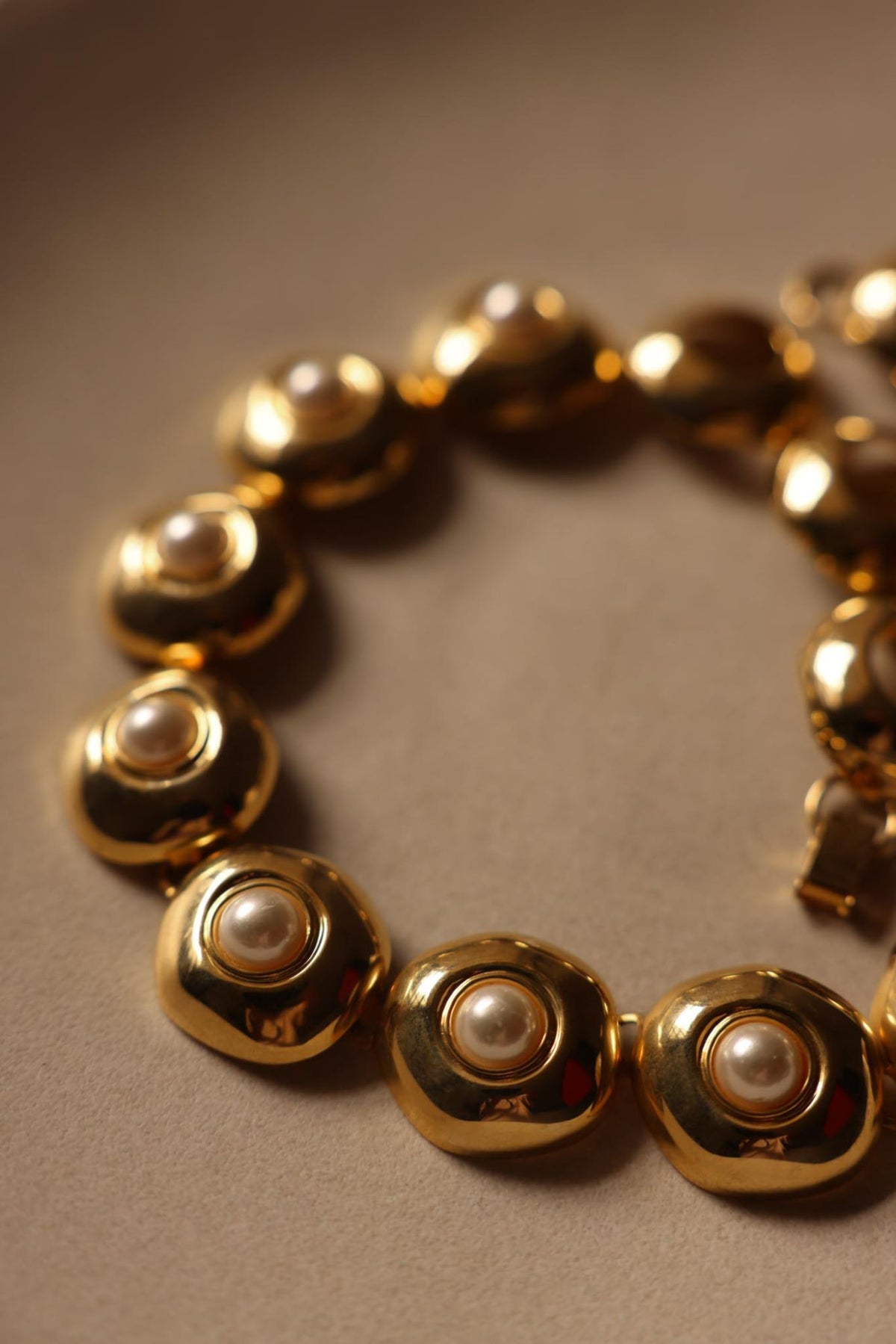 Close-up of bezel-set faux pearl cabochons in high-polish gold tone links