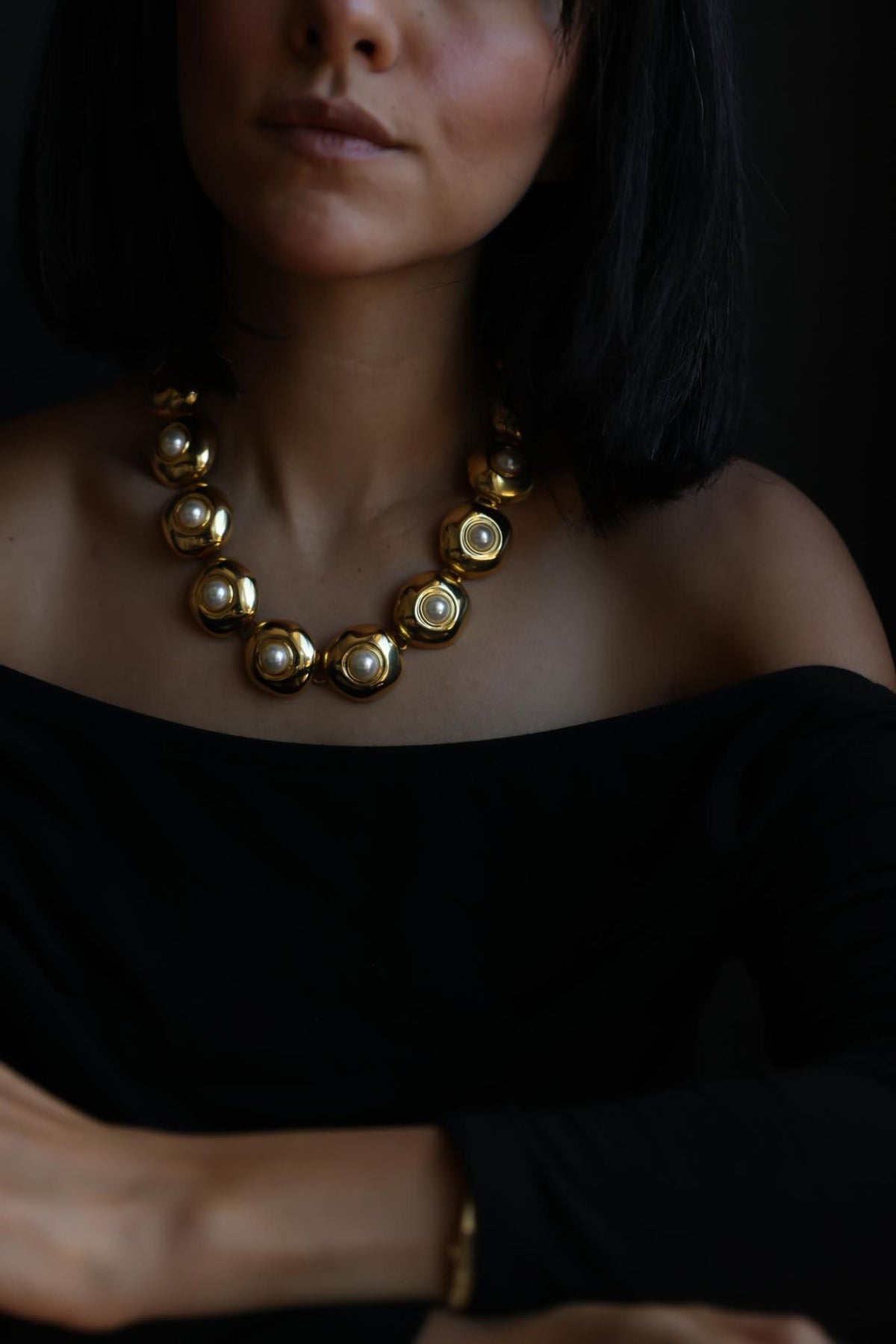 Side view of gold tone faux pearl link collar necklace worn