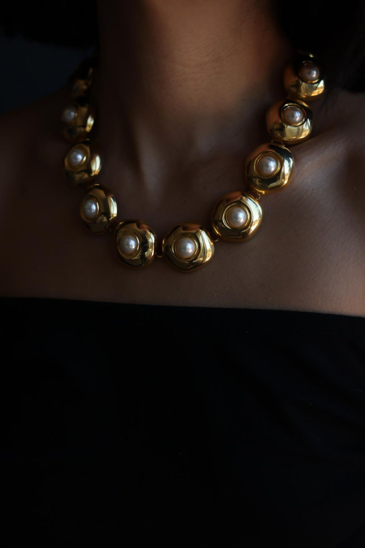 Close-up of gold tone faux pearl link necklace worn at the collarbone