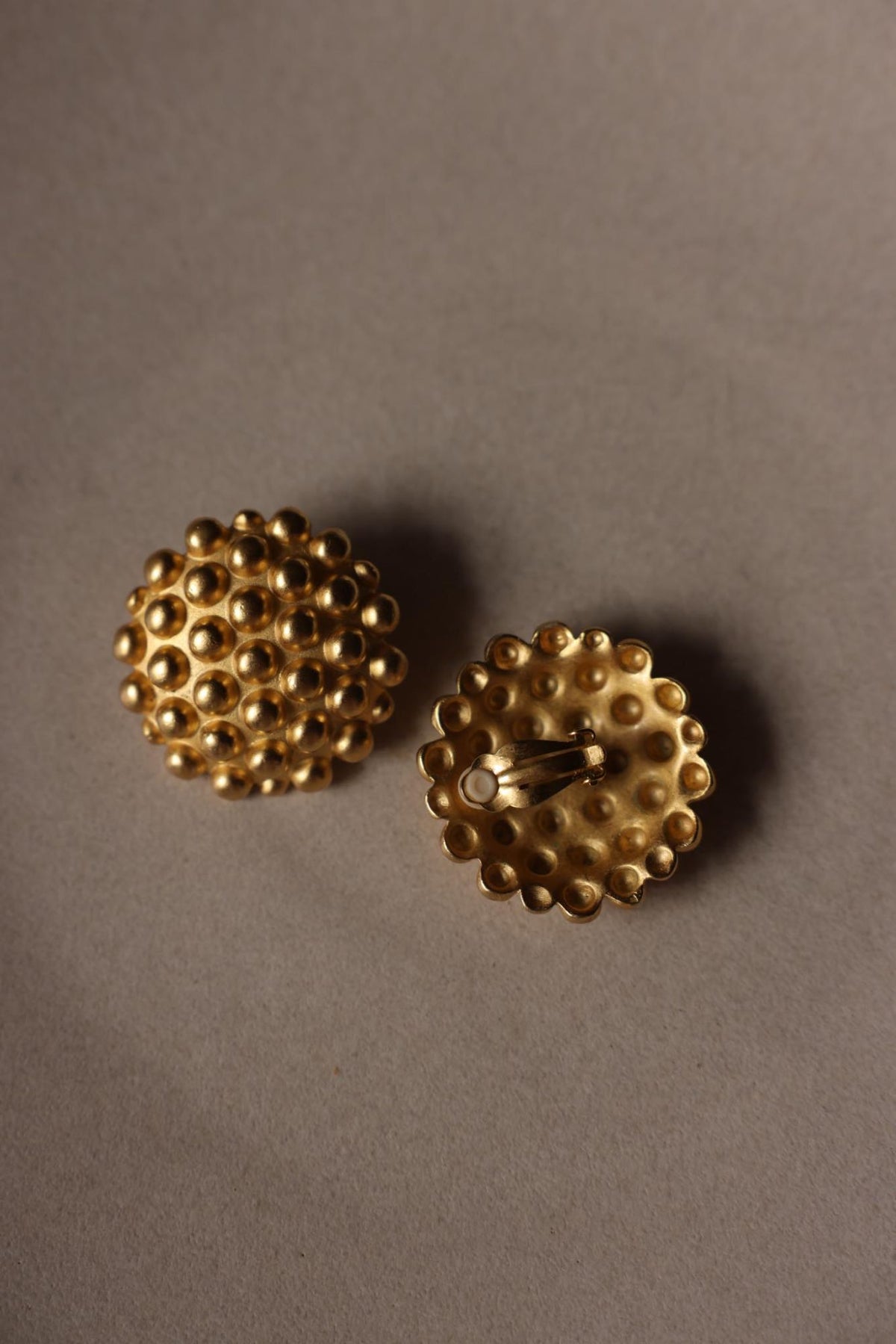 Front and clip-on back of matte gold tone studded dome earrings