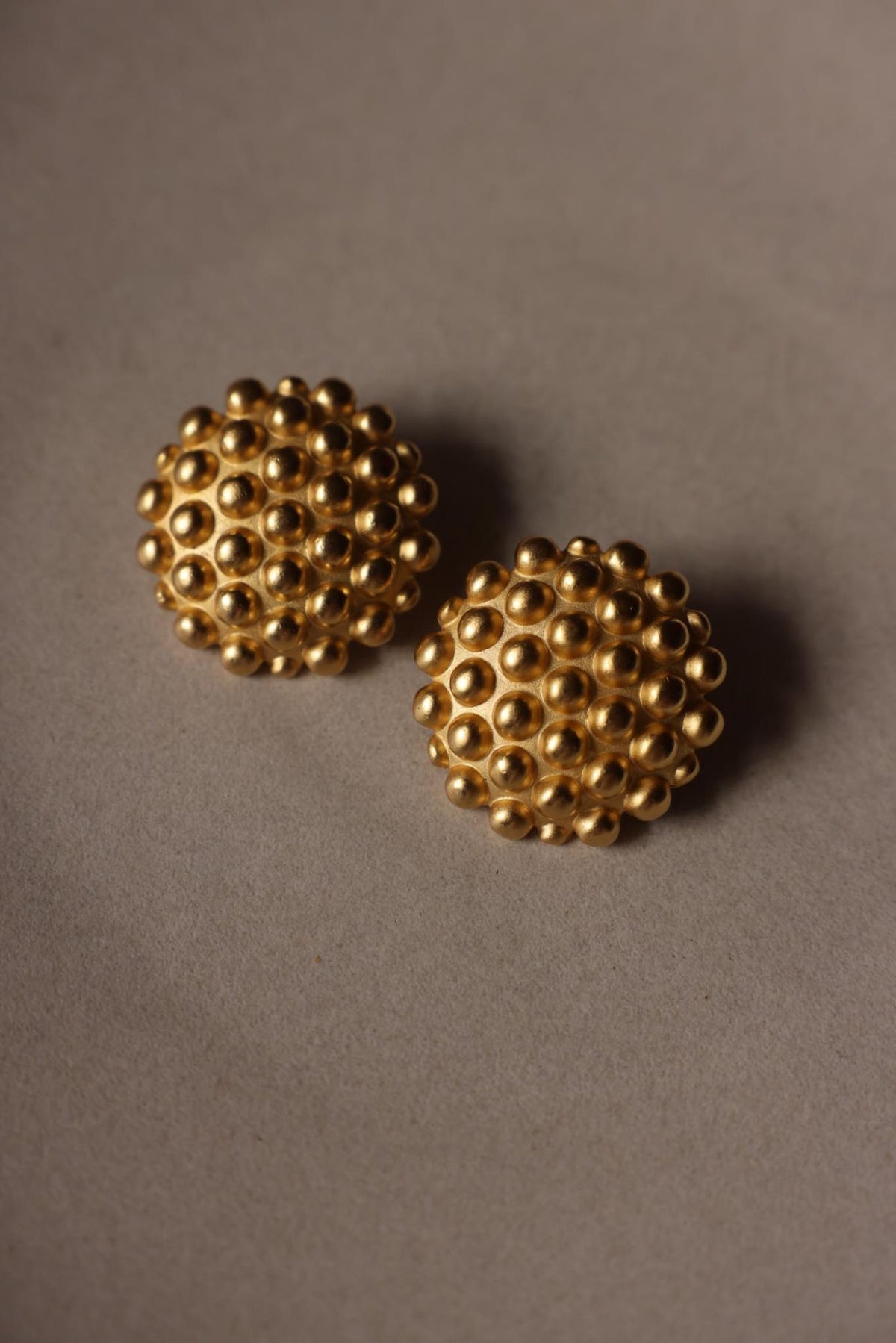 Front view of matte gold tone studded dome clip-on earrings