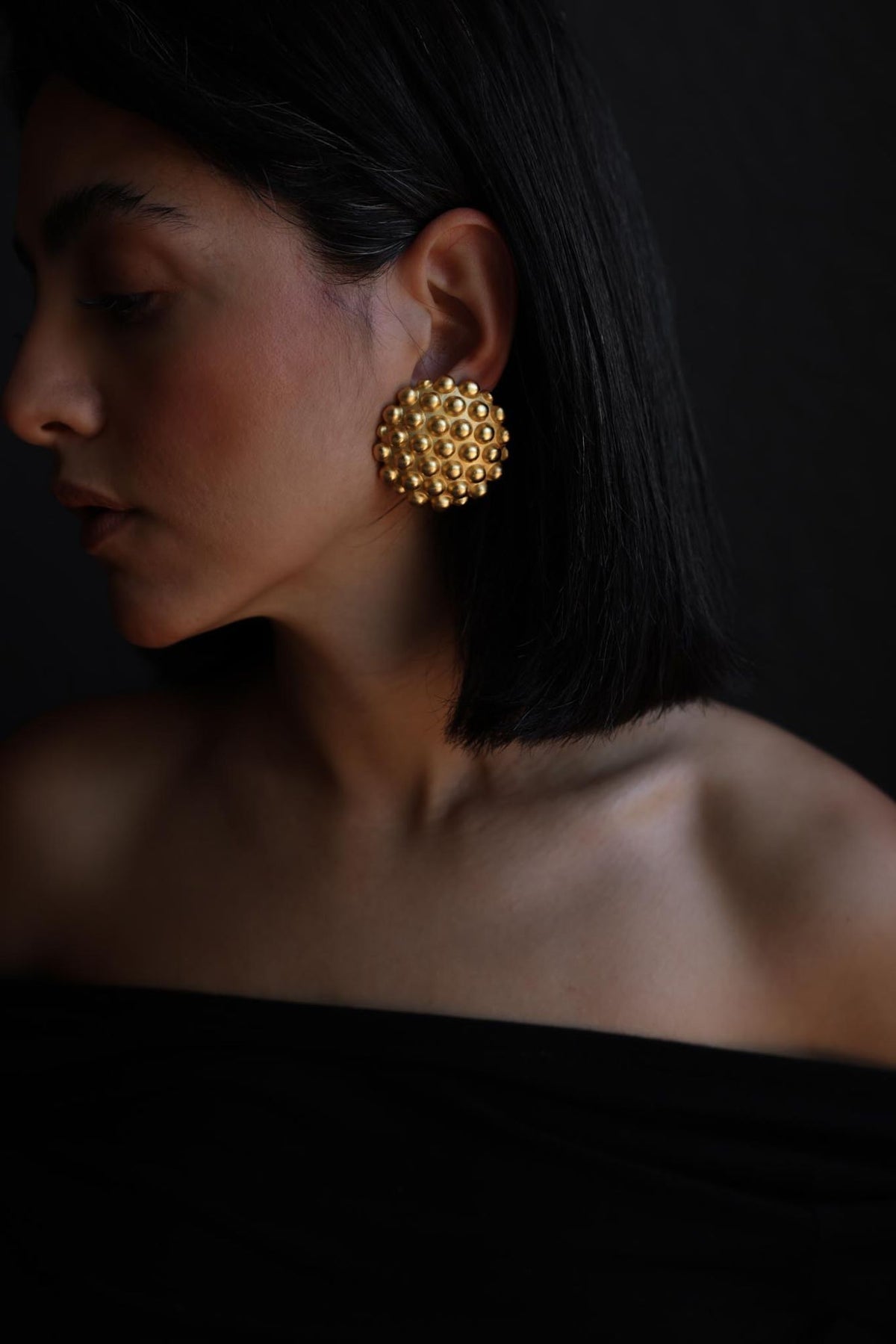 Matte gold tone studded dome clip-on earring worn