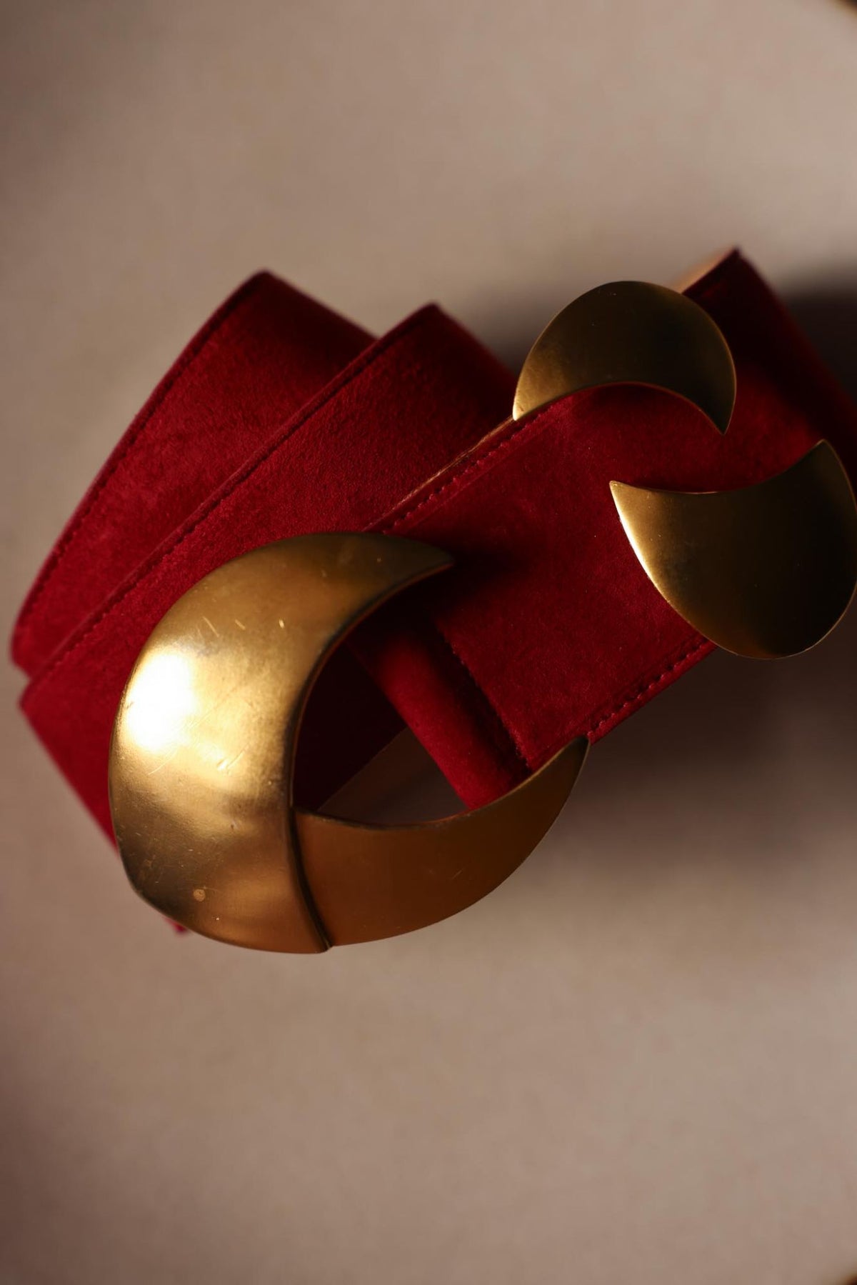 Angled view of the sculptural matte gold tone crescent buckle