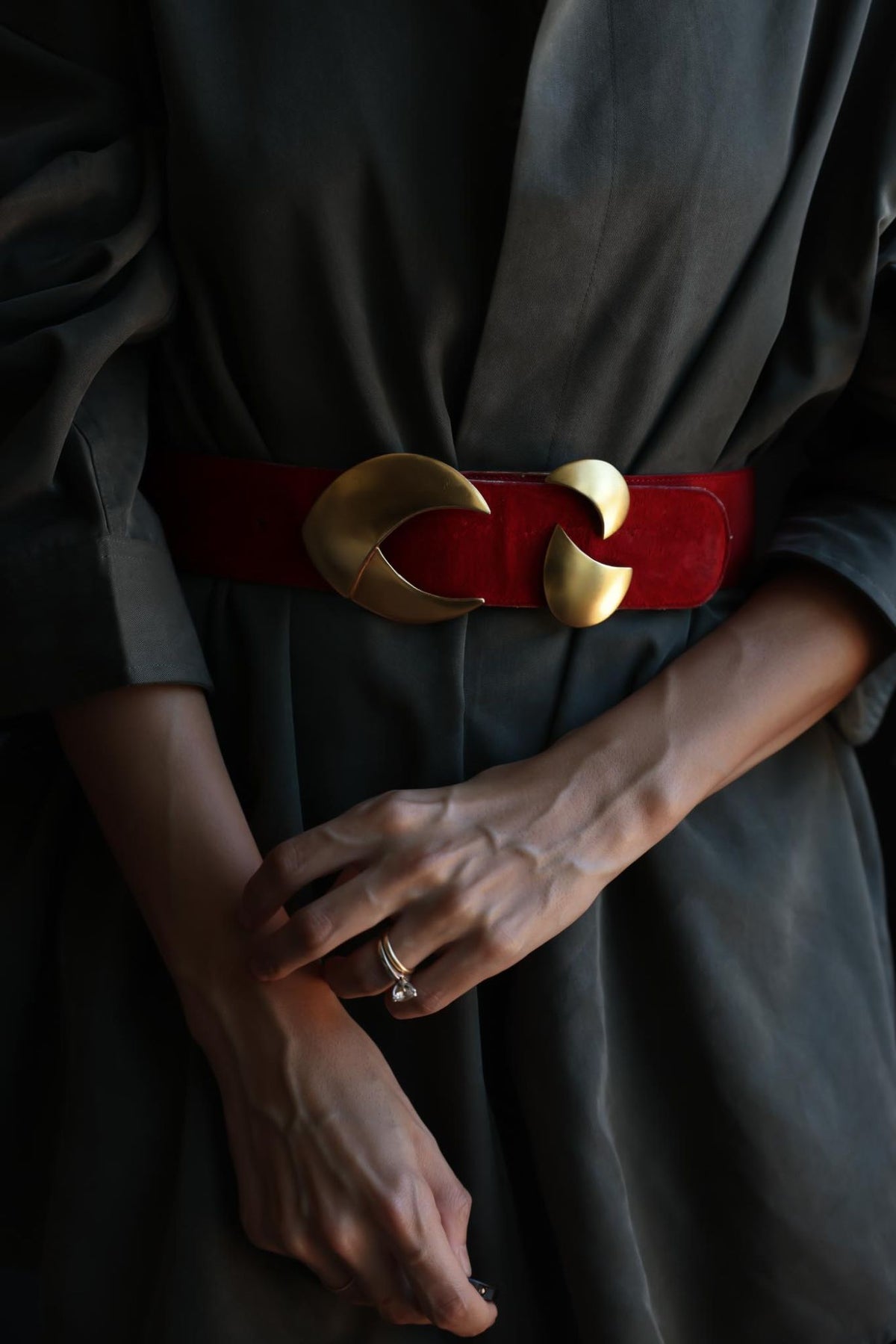 Red suede crescent buckle belt worn at the waist over a dark dress